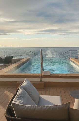 Color photo, aft deck of the SH Diana, looking over the infinity pool to the ship's wake and horizon.